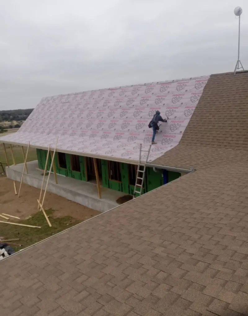 Worker preparing underlayment for a metal roof installation in Goulds